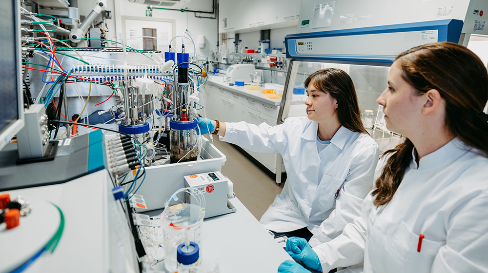 Stefanie Duvigneau (rechts) und Anna-Sophie Neumann (links) arbeiten gemeinsam im Labor an der Biopolymerproduktionsanlage