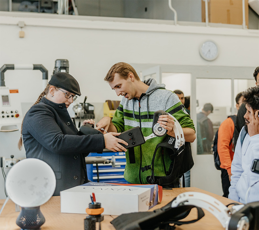 Henri Paetz zeigt Interessierten in der StudierendenWerkstatt die Exoskelettarme (c) Hannah Theile Uni Magdeburg