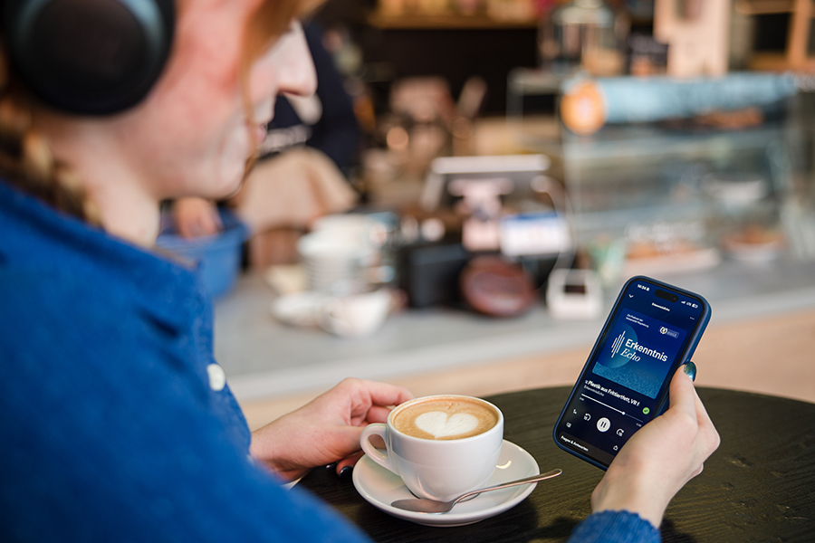 Junge Frau hört in einem Café den Wissenschaftspodcast der Uni Magdeburg auf ihrem Smartphone (c) Jana Dünnhaupt Uni Magdeburg