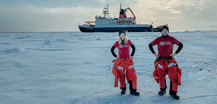 Dr. Mehlmann und Prof. Richter stehen auf dem Eis, hinter ihnen das Schiff Polarstern (c) Alfred-Wegener-Institut : Esther Horvath