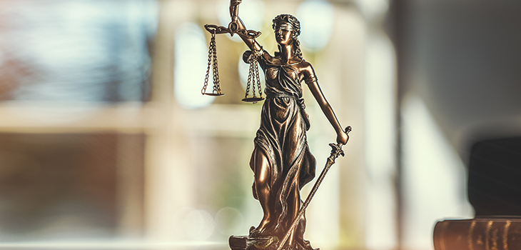 Die Statue der Gerechtigkeit Lady Justice in Bronze steht auf einem Schreibtisch (Foto: Shutterstock / Audio und werbung)