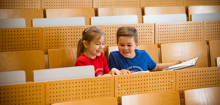 2 Kinder sitzen im Hörsaal und lachen zusammen (c) Jana Dünnhaupt Uni Magdeburg