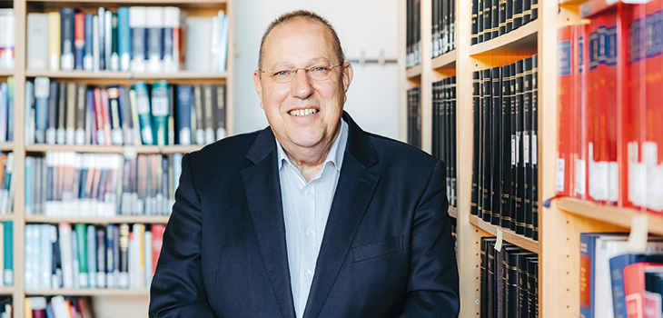 Portrait von Prof. Burgard vor zwei Bücherregalen in seinem Büro (Foto: Jana Dünnhaupt / Uni Magdeburg)
