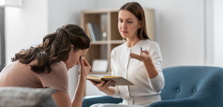 Psychologin mit Notizbuch, die mit gestressten Patientin während der Psychotherapie-Sitzung spricht (Foto: Shutterstock / Ground Picture)