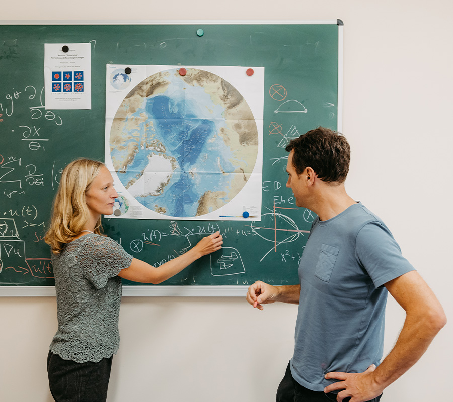 Bild von zwei Menschen, die an einer Tafel stehen und über Mathe reden. (Foto: Jana Dünnhaupt/Uni Magdeburg)