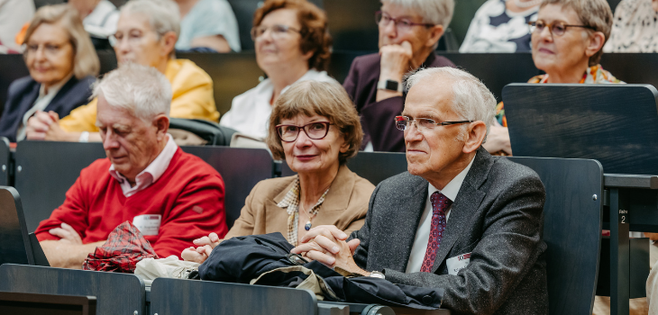 Aufmerksame Zuhörerinnen und Zuhörer im Festakt Mehrere ältere Frauen und Männer sitzen in einem Hörsaal und hören aufmerksam zu. In der vorderen Reihe sind drei Personen gut zu erkennen – eine Frau mit Brille in der Mitte, ein Mann im roten Pullover links und ein Mann im grauen Anzug rechts. Hinter ihnen sitzen weitere Gäste, die konzentriert nach vorn blicken ©Jana Dünnhaupt, Uni Magdeburg